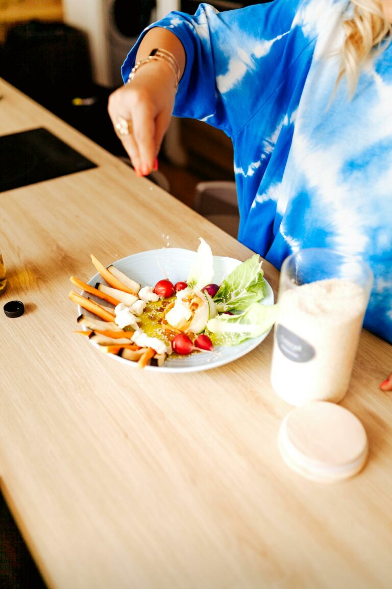 A chef preparing a fresh vegetable salad on a wooden table in a modern kitchen setting.