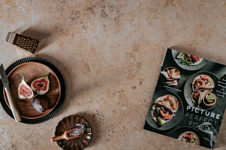 A flat lay shot featuring figs, a knife, and a cookbook on a rustic surface.