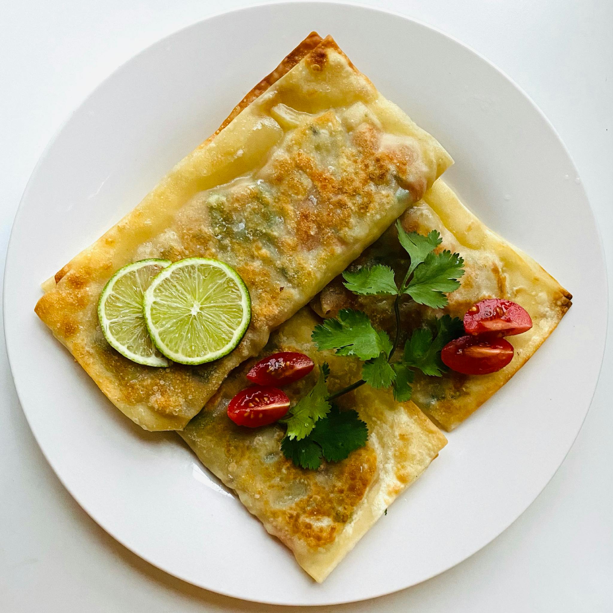 Crispy pancakes topped with fresh lime slices, cherry tomatoes, and herbs.